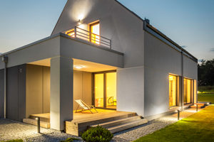 Exterior of illuminated house among green Night external view of a contemporary house with outdoor lighting